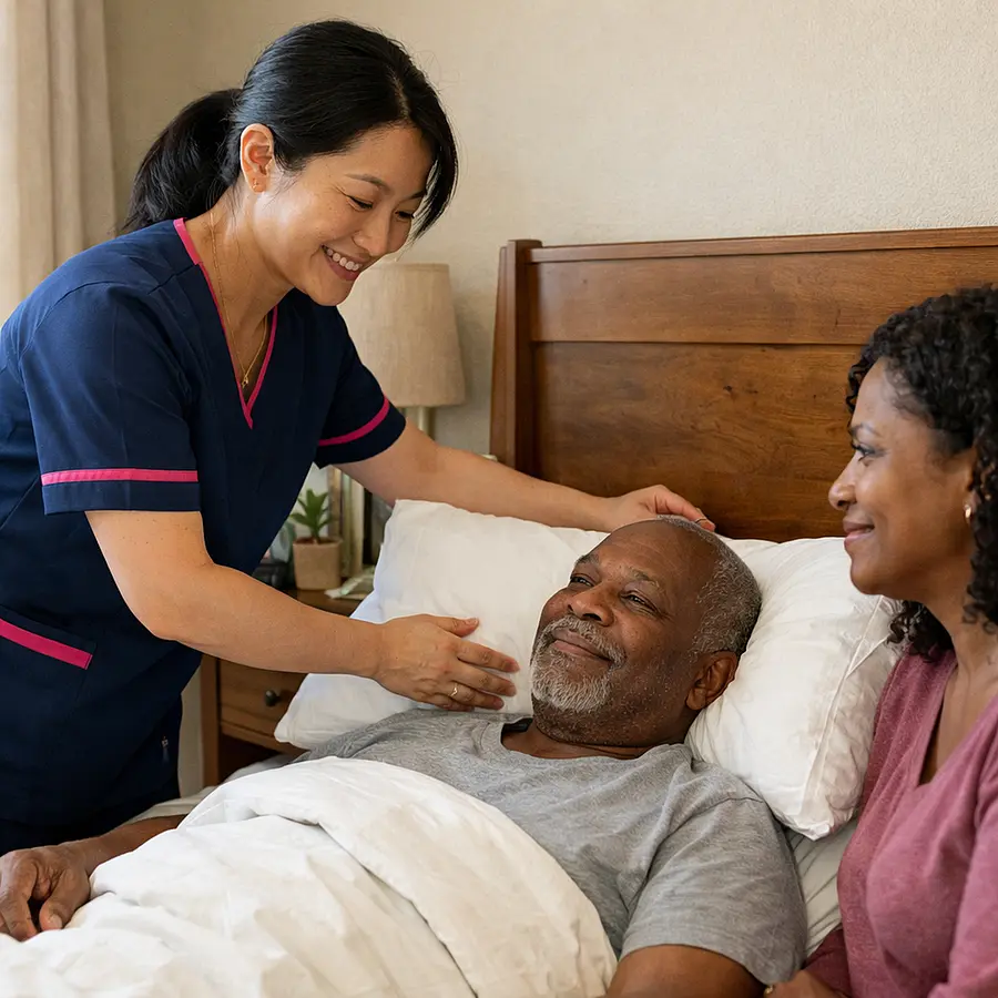 A realistic close home care scene showing an asian female caregiver in a tunic uniform colour 00072b with e51974 accent gently raising pillows for a black male service user in bed family member nearby looking reassured natural bedroom setting calm facial expressions warm and supportive mood